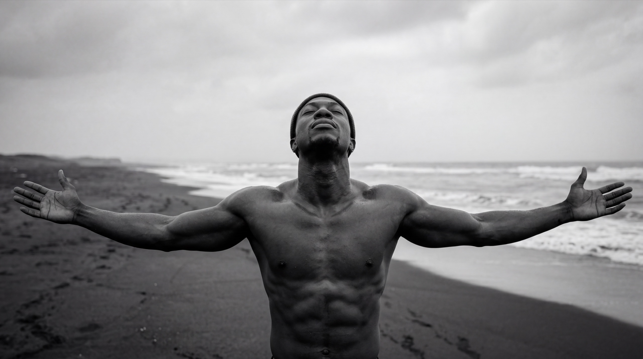 Noah Priest, arms open on a black-sand beach